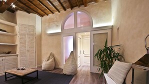 A cozy living room with a wooden coffee table, beige cushions, a sofa, and a large green plant. - Giglio Santa Trinita (Florence)
