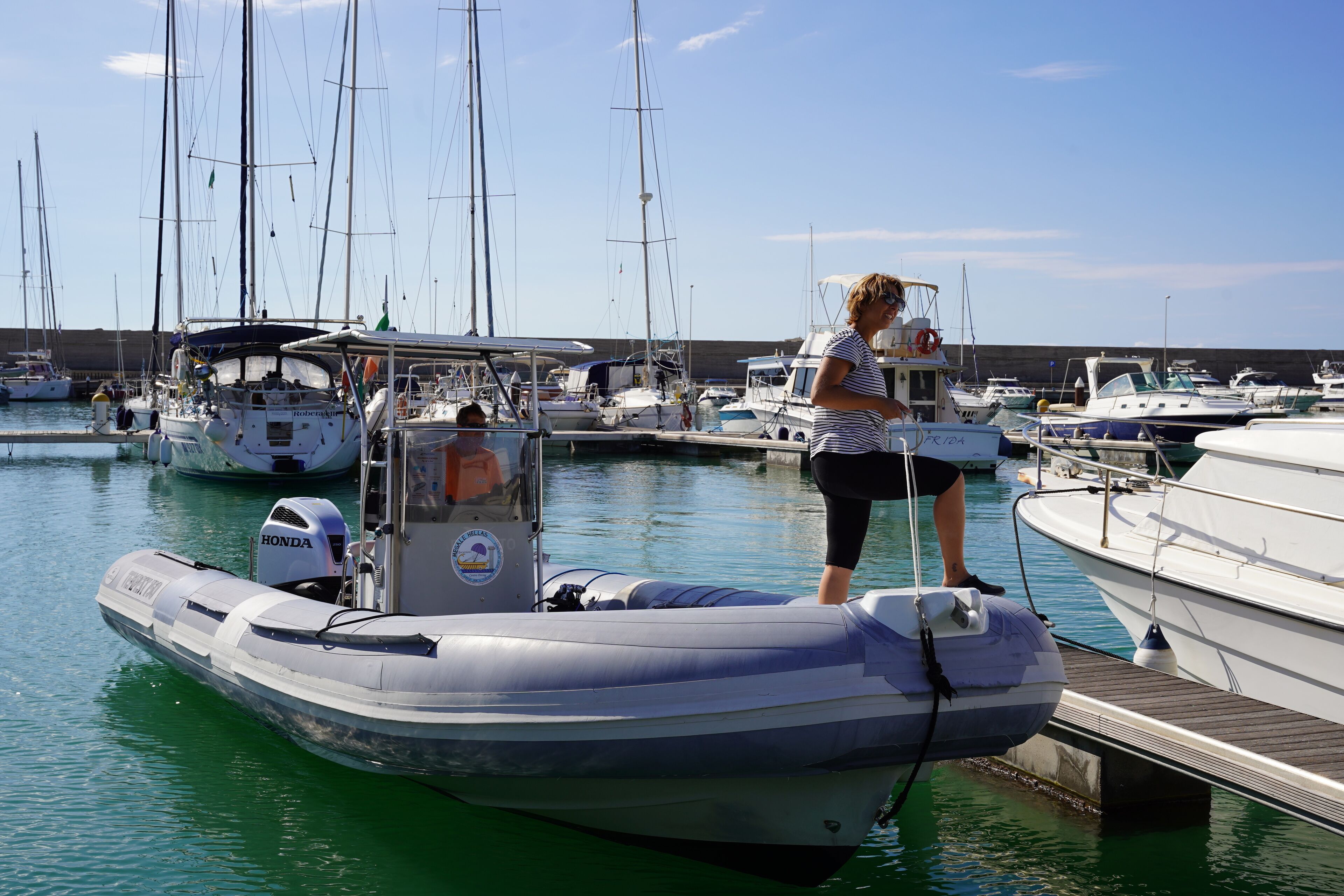 Ein Yachthafen mit verschiedenen Schiffen, darunter ein Motorboot mit einem Honda Außenborder.