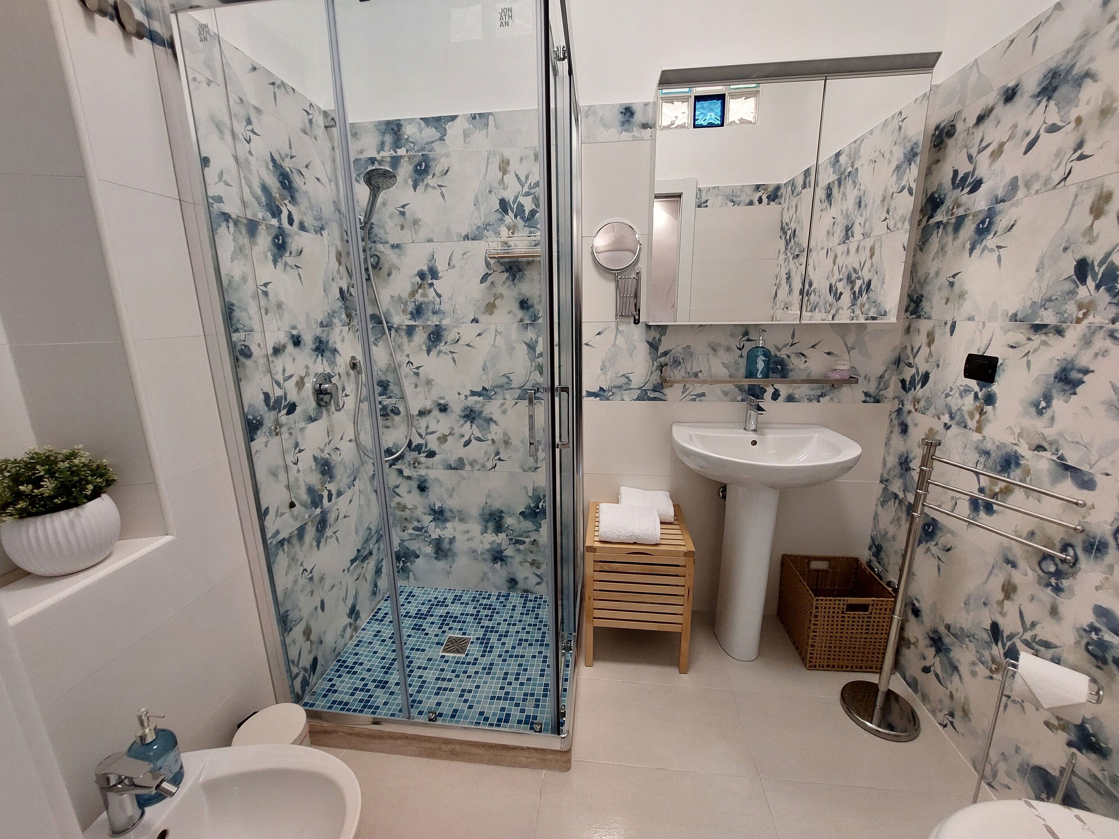 A bathroom with a glass-enclosed shower, a white sink, and a mirror above it.
