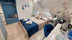 Une chambre d’hôtel avec un lit, un bureau, une chaise et une armoire.