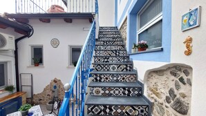 Un escalier orné de carreaux décoratifs, une rampe bleue et un mur en pierre.