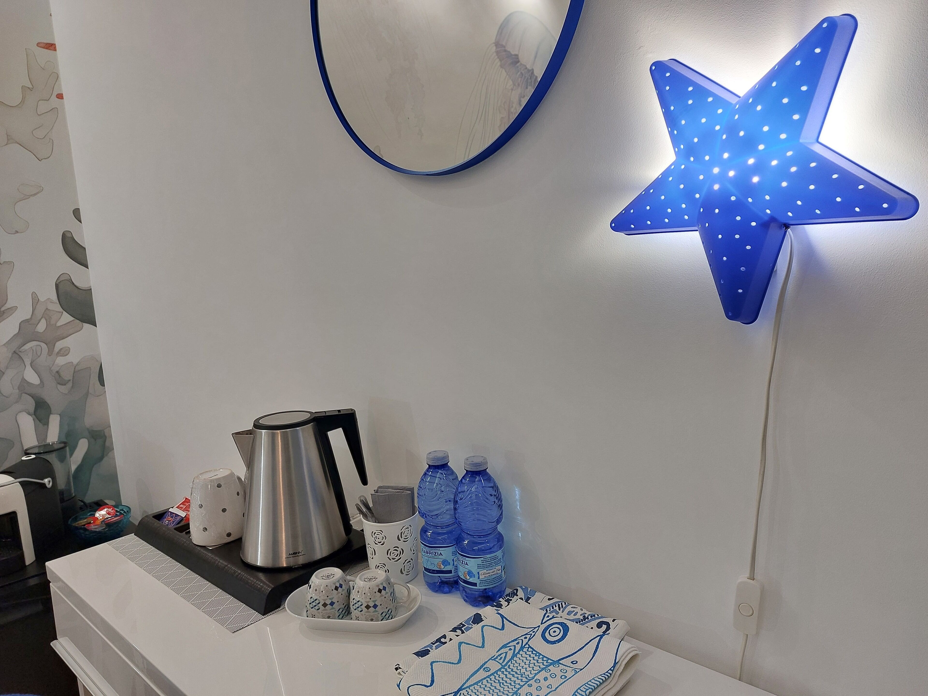 Eine Küchenarbeitsplatte mit einem Wasserkocher, Wasserflaschen, einem Teller mit Salzstreuern und einer dekorativen Sternlampe.