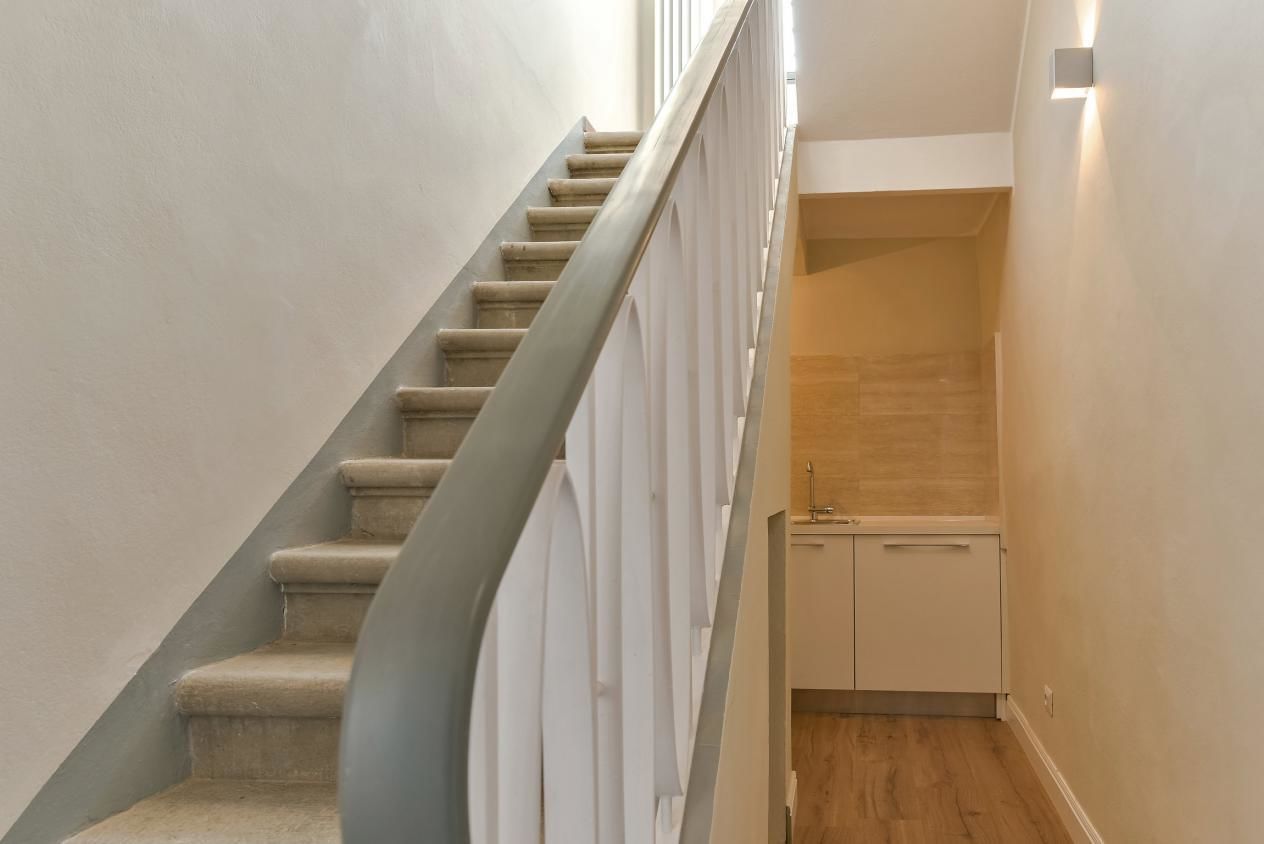 A staircase with a handrail and a small cabinet at the bottom.