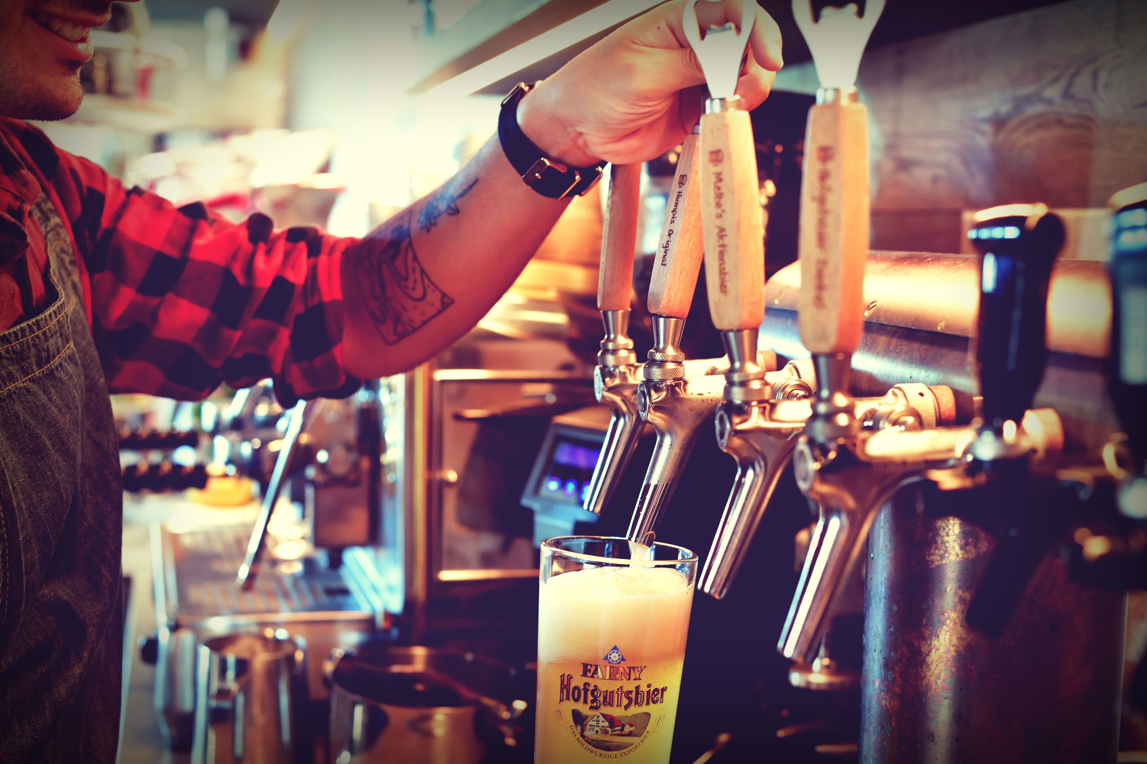 Ein Barkeeper schenkt Bier in ein Glas ein.