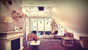 A cozy living room with a fireplace, a hanging chair, and a view of the outside. - Melbo’s Home (Lindau)