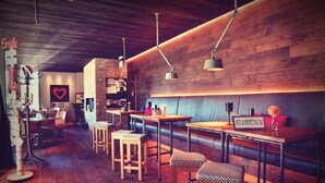 A cozy restaurant with wooden tables and benches, a brick wall, and hanging pendant lights. - Melbo’s Home (Lindau)