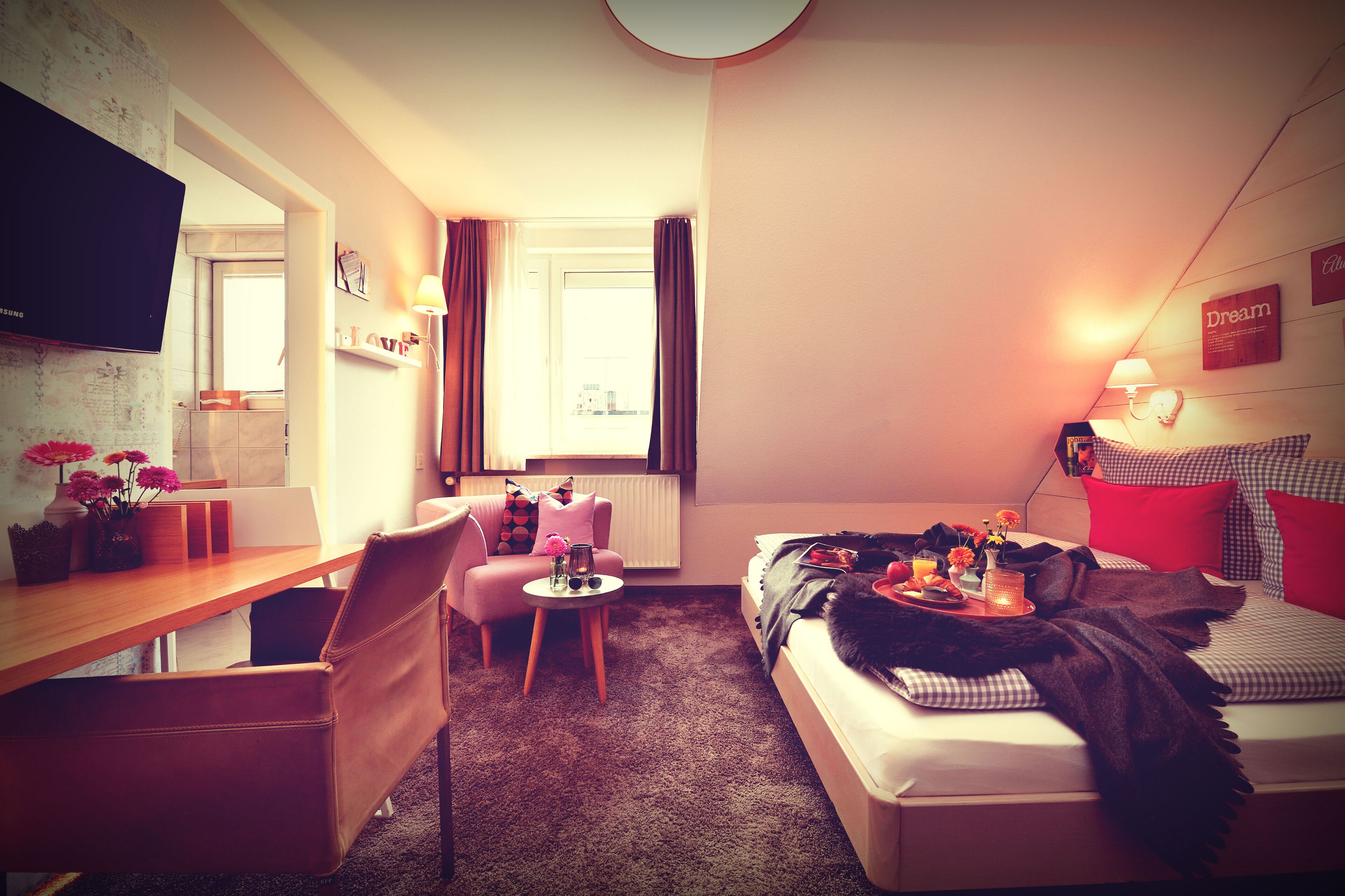 Ein gemütliches Hotelzimmer mit Bett, Schreibtisch, Stuhl und Fernseher.