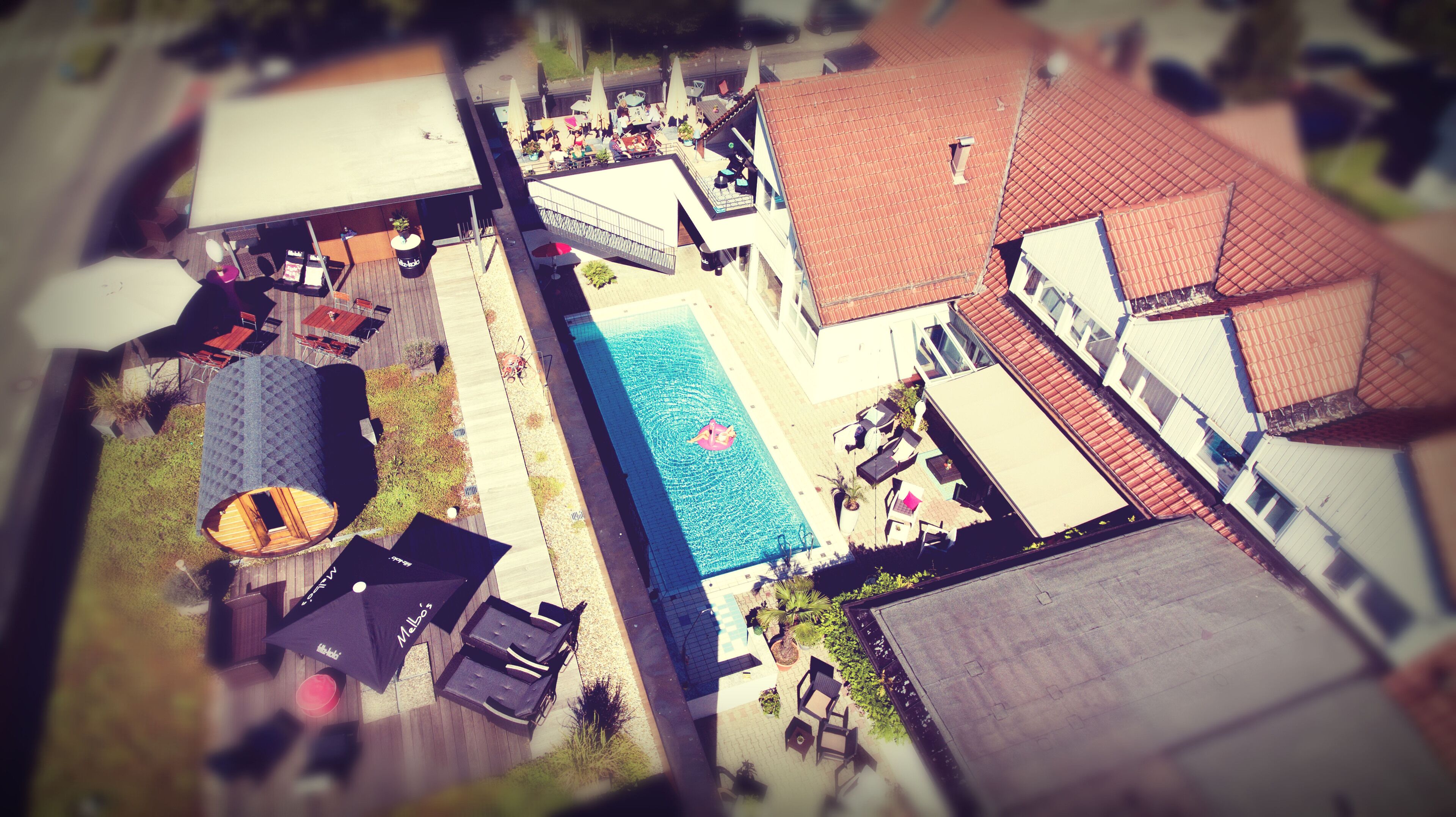 Una vista aerea di una zona residenziale con piscina, area relax all'aperto e diversi edifici.