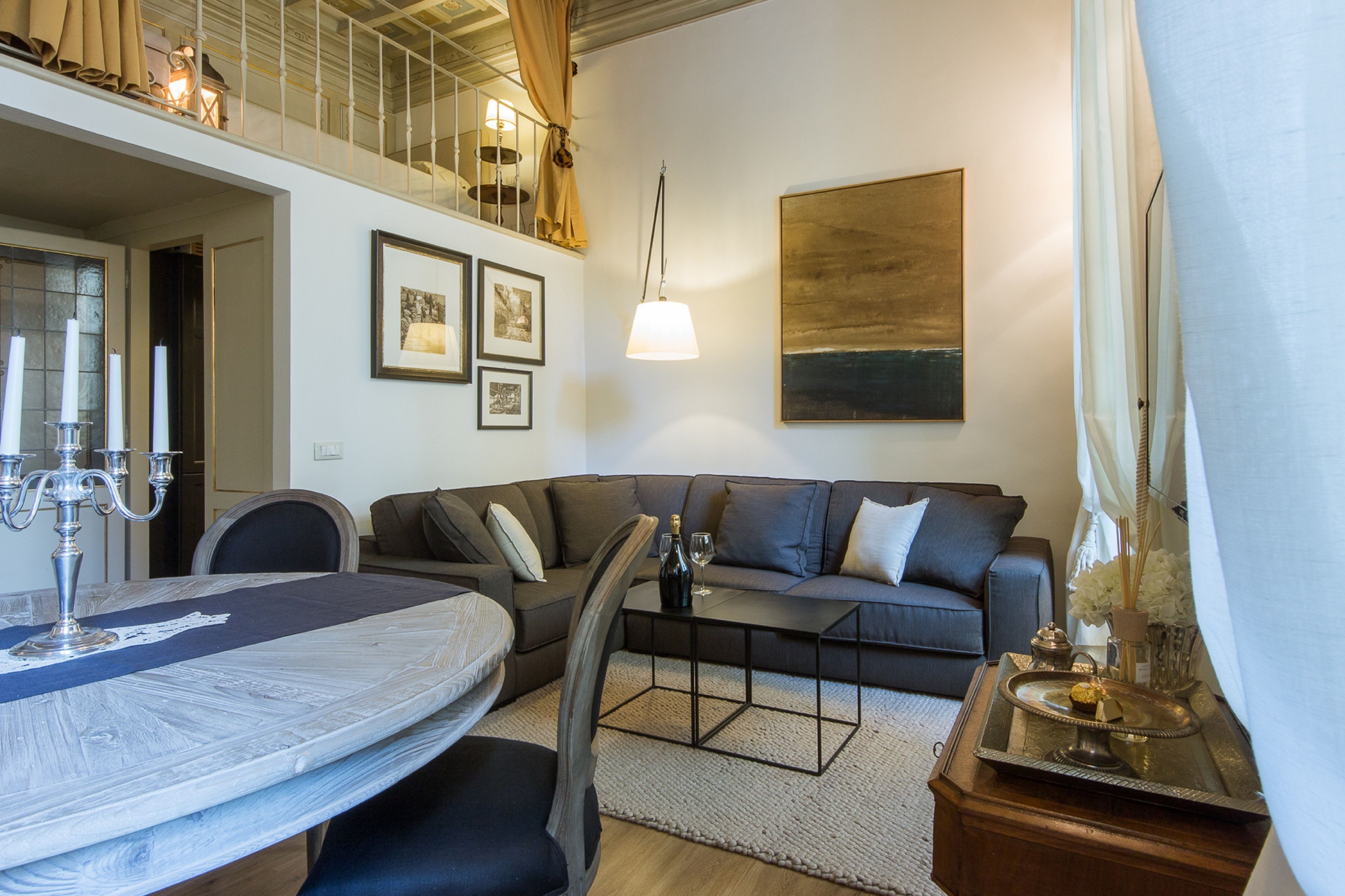 A modern living room with a sofa, coffee table, and a dining table set with candles.