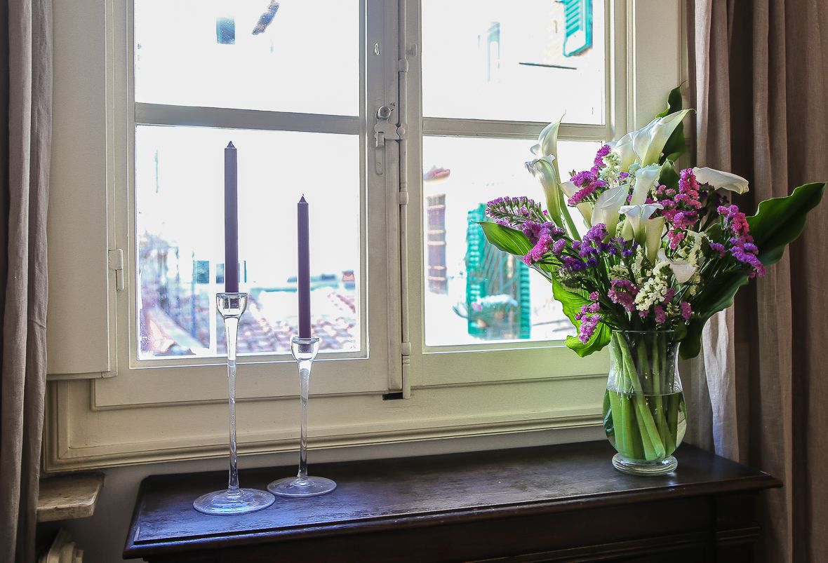 A window with a candle holder and a vase of flowers on a wooden ledge.