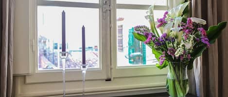 A window with a candle holder and a vase of flowers on a wooden ledge.