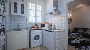 A compact kitchen with a washing machine, microwave, and a window with blinds. - Pandolfini Roof (Florence)