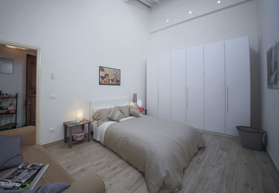 A bedroom with a bed, a nightstand, a wardrobe, and a painting on the wall.