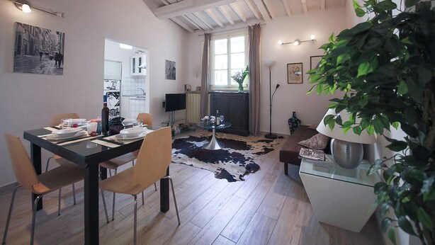 A dining area with a table set for four, a fireplace, and a large plant in the foreground. - Pandolfini Roof (Florence)