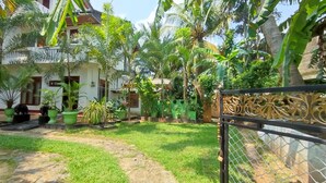 A garden with various plants and a house in the background. - Matota Family Villa (Matara)