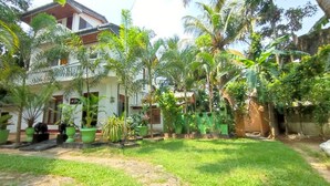 A courtyard with a house, surrounded by lush greenery and potted plants. - Matota Family Villa (Matara)