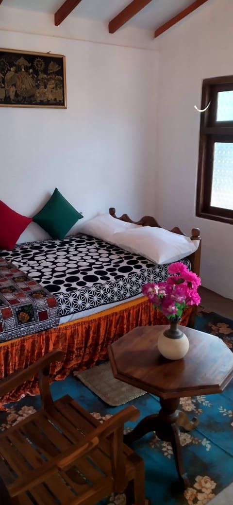 Ein Zimmer mit einem Bett, einem Tisch mit einer Vase und einem Sessel.
