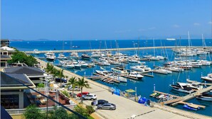 A marina with numerous boats docked, a clear blue sky, and a view of the sea. - Sanya Serenity Coast Marina Hotel (Sanya)