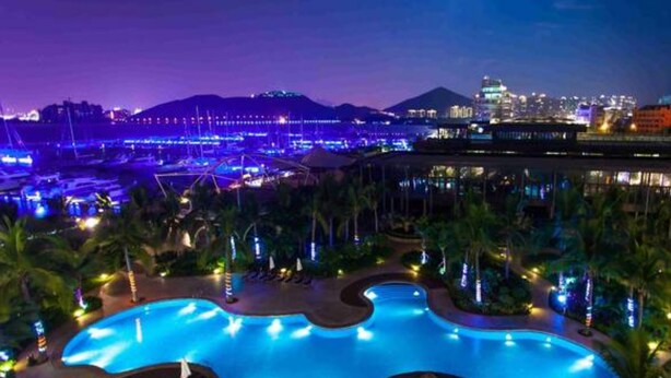 A nighttime view of a resort with a large pool, palm trees, and city lights in the background. - Sanya Serenity Coast Marina Hotel (Sanya)