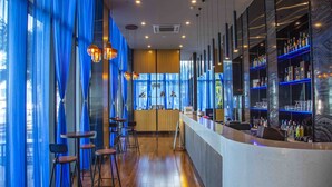 A bar area with a curved counter, bar stools, and shelves stocked with bottles. - Sanya Serenity Coast Marina Hotel (Sanya)