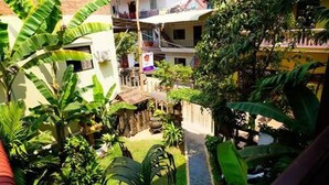 A courtyard with lush greenery, a small water feature, and a pathway leading to a building with balconies. - Uncle Sam Villa (Siem Reap)