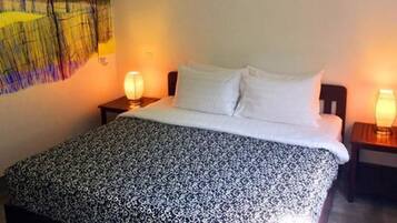 Un dormitorio con una cama, dos lámparas de noche, una lámpara de pared y un cuadro de paisaje.