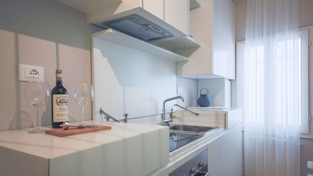 Una cocina moderna con horno empotrado, un fregadero y una botella de vino sobre la encimera.