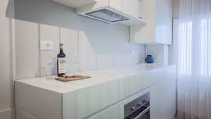 Una cocina moderna con una encimera blanca, una botella de vino y una copa.