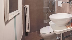 Un baño pequeño con inodoro, lavamanos, ducha y ventana.
