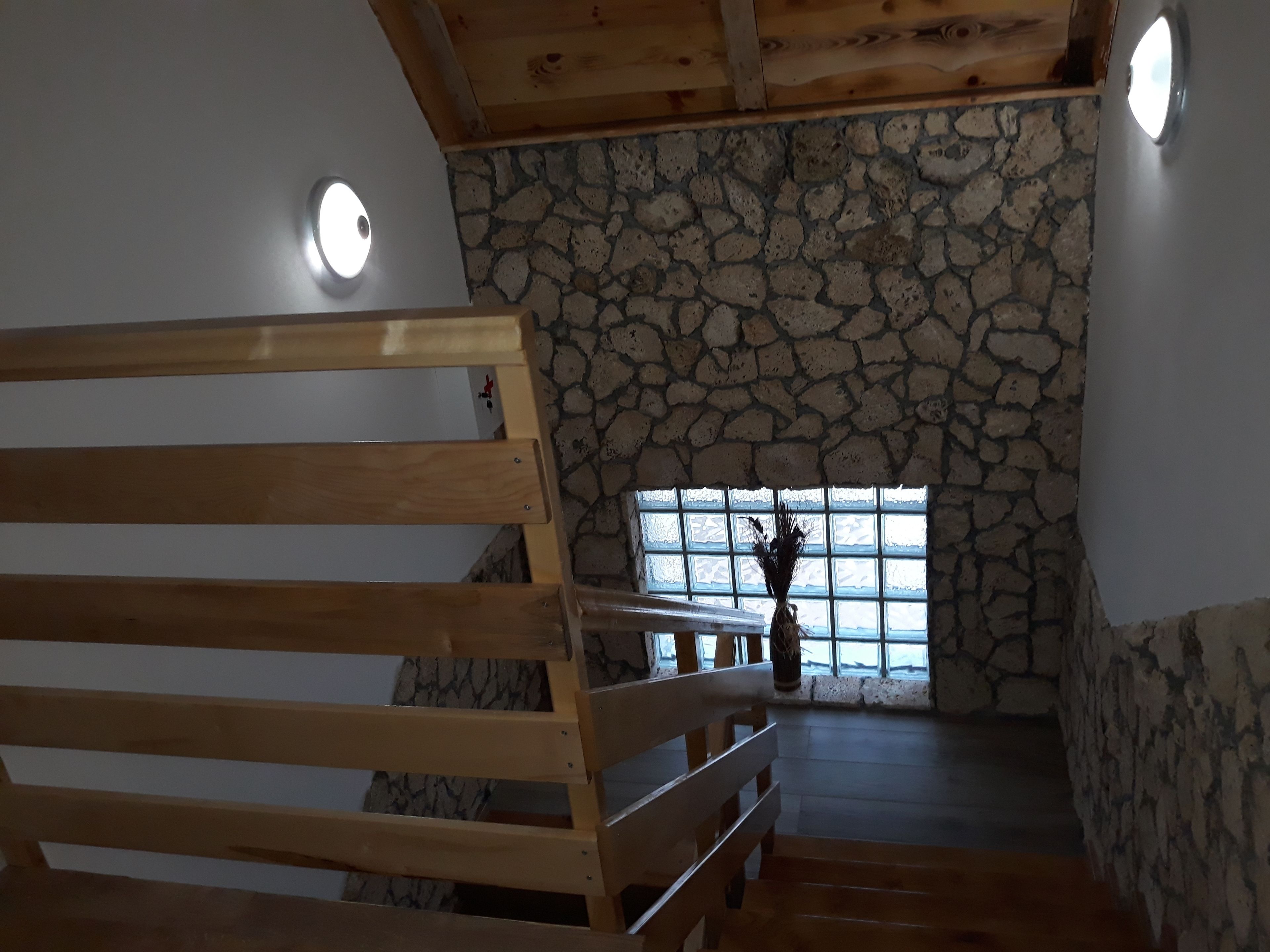A wooden bench in a room with stone walls and a window.