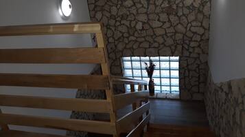 A wooden bench in a room with stone walls and a window.