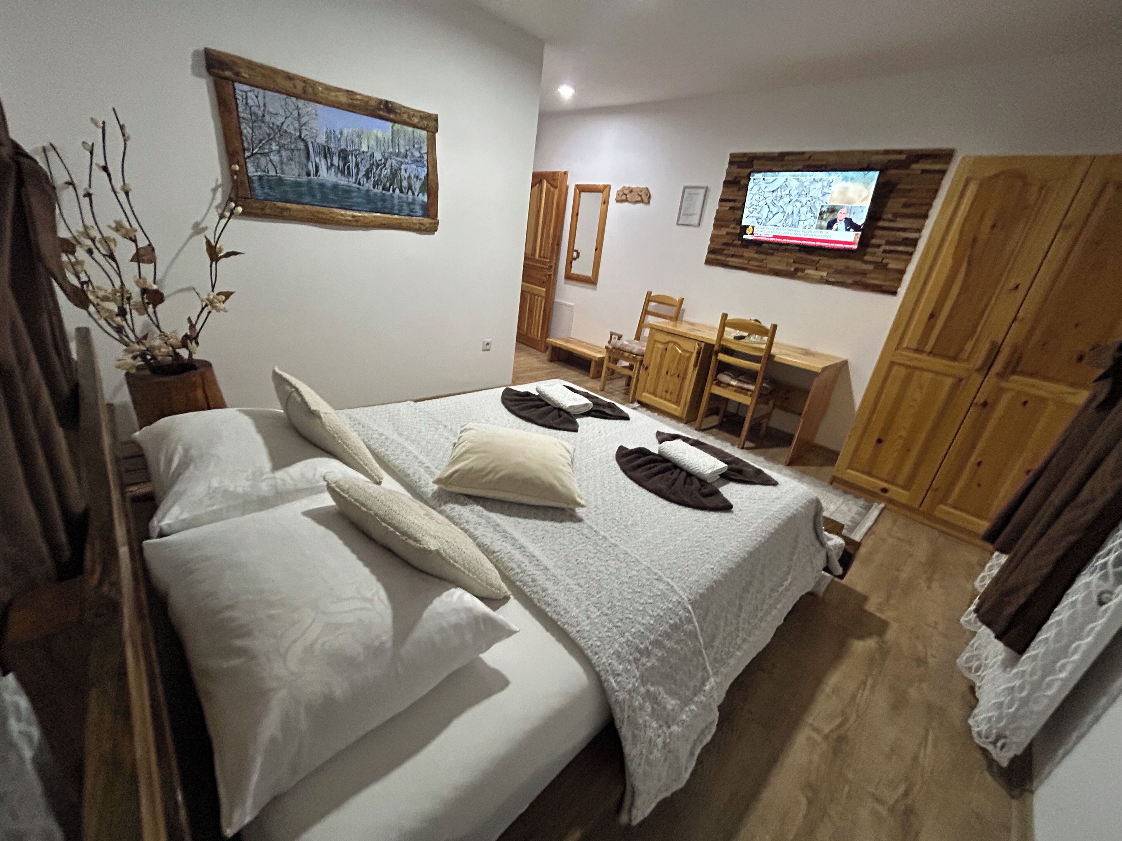 A bedroom with a bed, a desk, and a television.