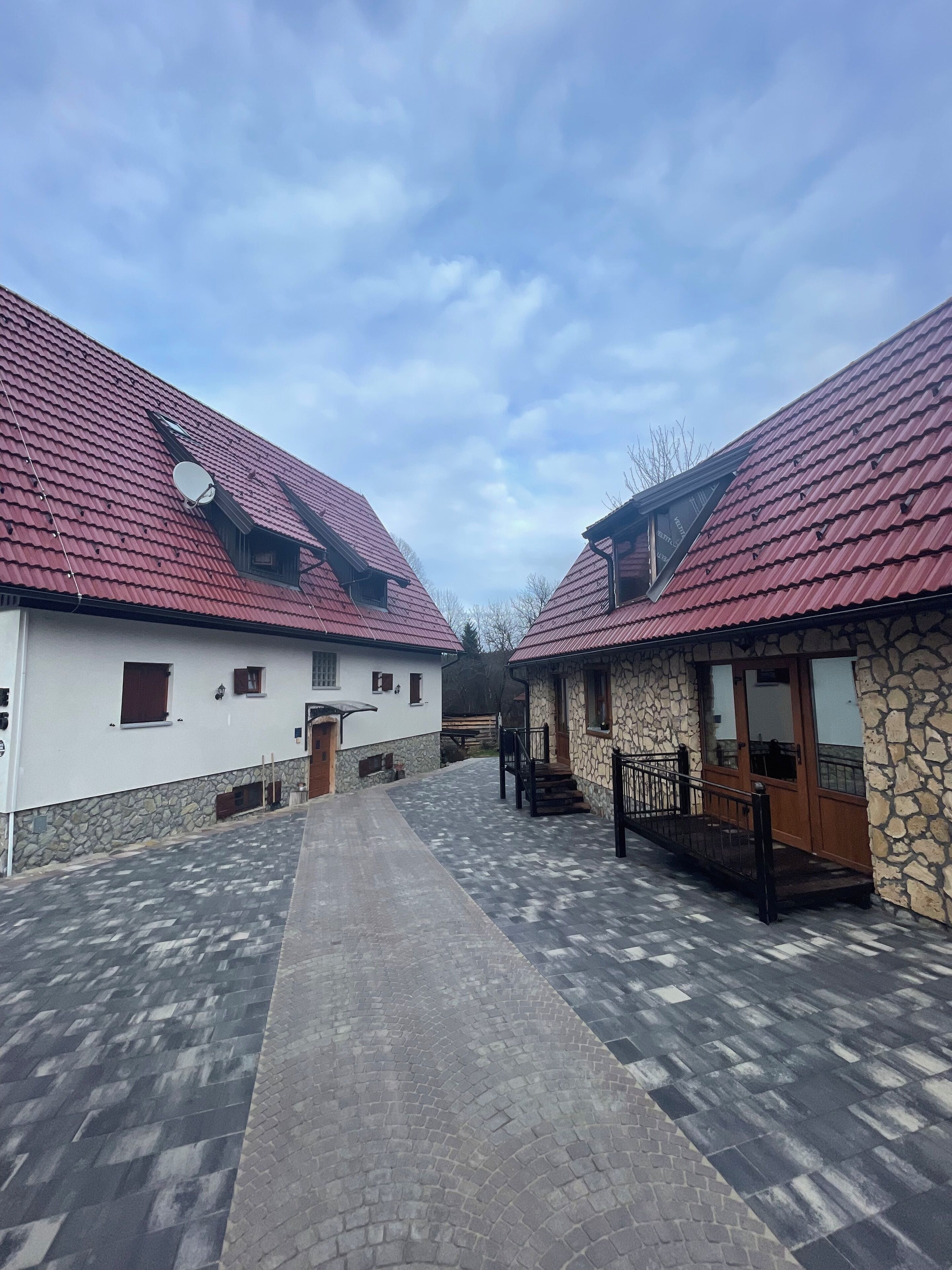 A courtyard with two buildings, one with a stone facade and the other with a white exterior.