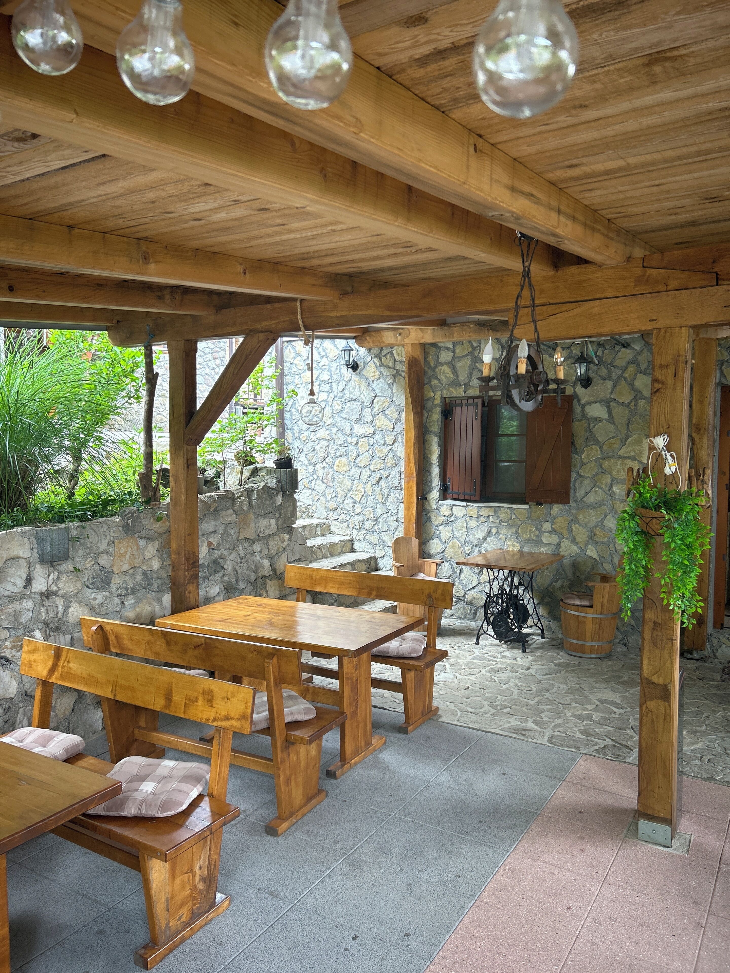 Un área de comedor rústica al aire libre con paredes y piso de piedra.