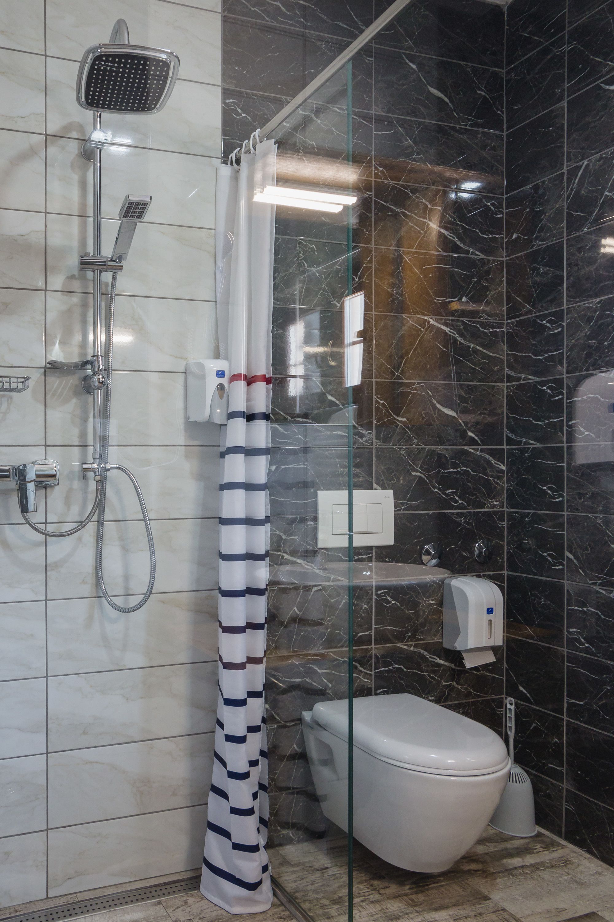 A bathroom with a shower, toilet, and hand dryer.
