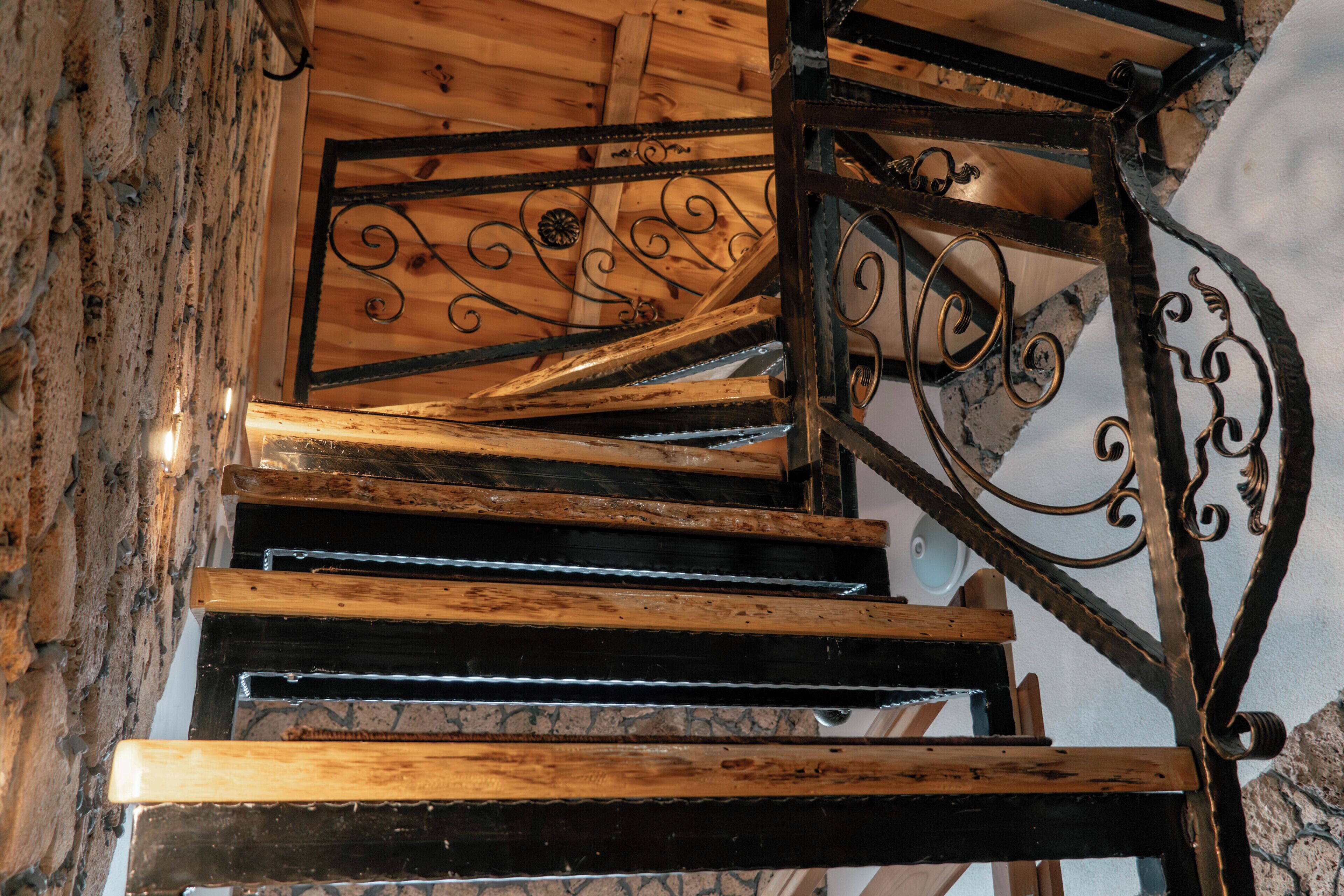 A wooden staircase with metal railings and a stone wall.