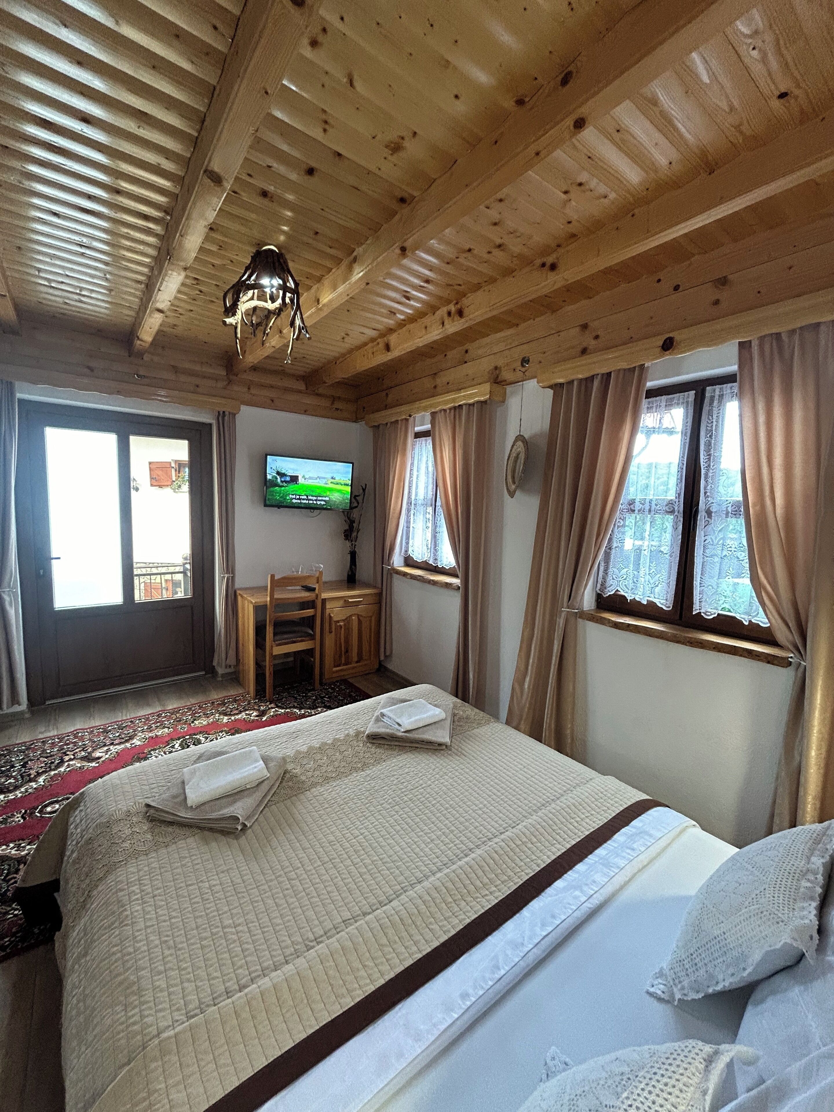 A wooden-paneled room with a bed, a desk, and a television.