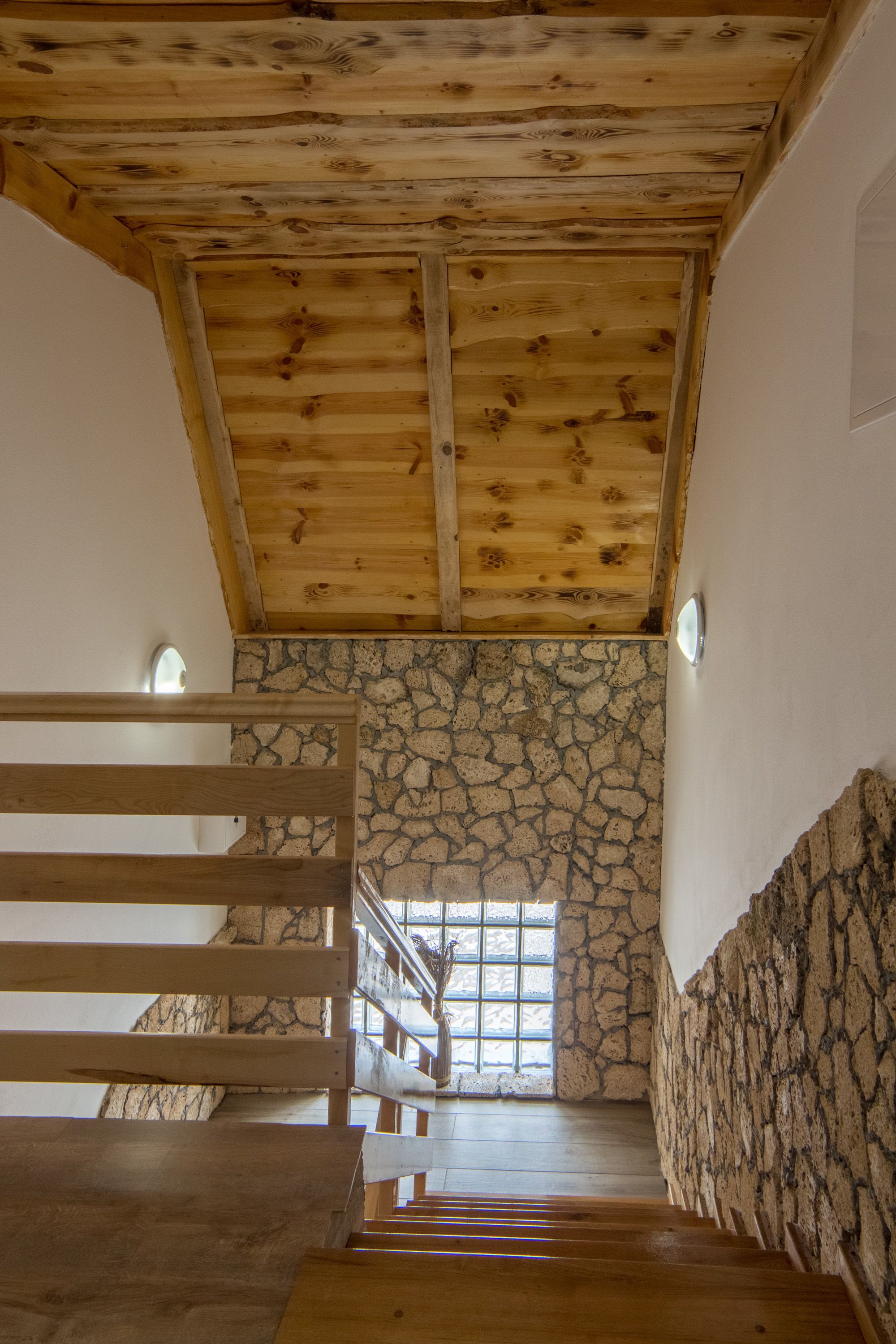 Una escalera de madera que conduce a un muro de piedra con una ventana.