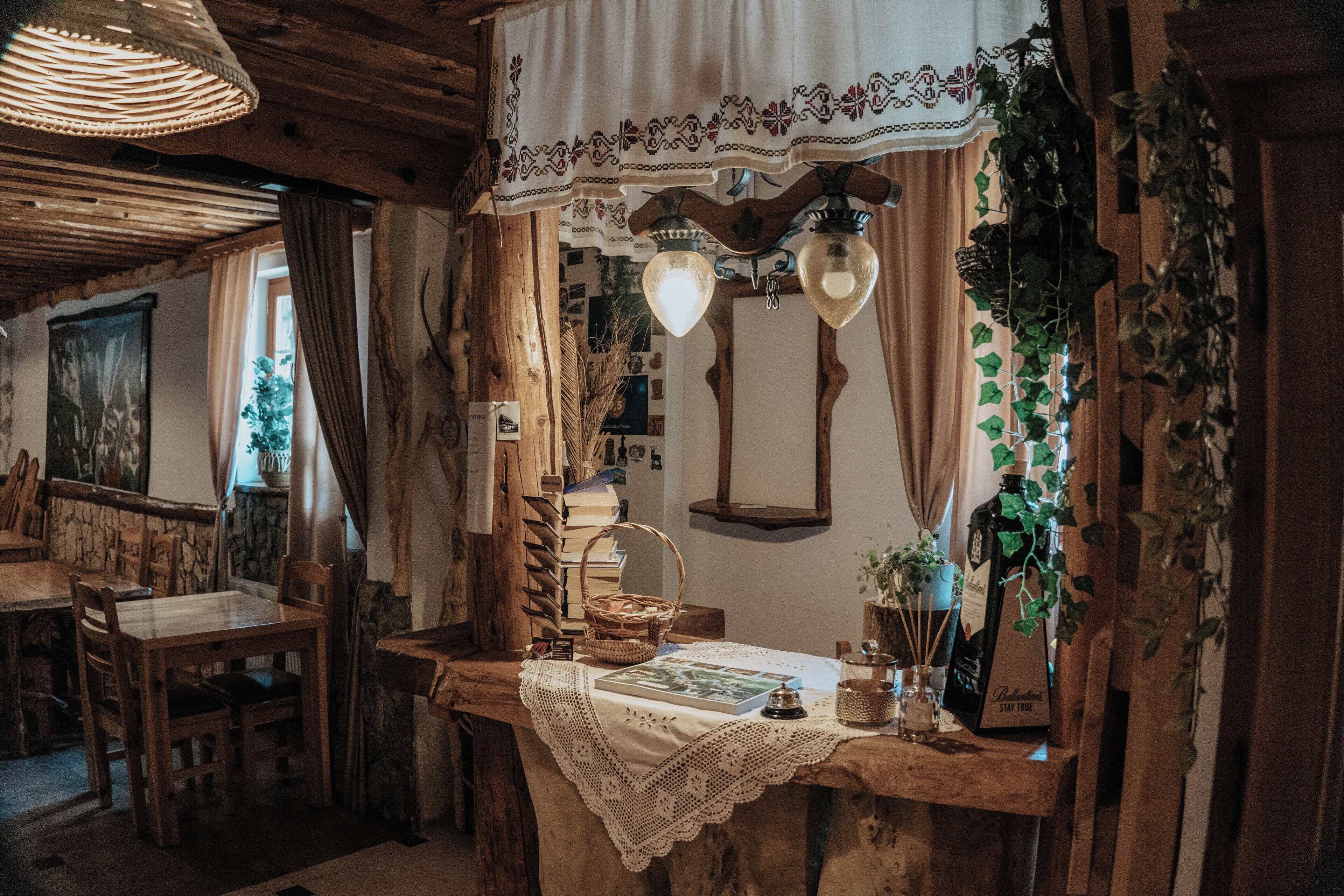 A rustic room with a wooden table, a bench, a decorative mirror, and a wall-mounted light fixture.