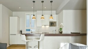 Una cocina moderna con armarios blancos, encimera de madera y dos taburetes de bar.