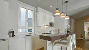 Una cocina moderna con armarios blancos, encimera de madera, cocina a gas y una barra con taburetes.