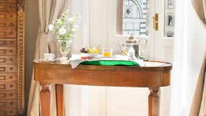 Une pièce avec une table en bois, un vase rempli de fleurs et une vue sur des bâtiments, visible à travers une porte ouverte.