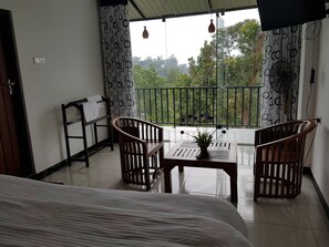 A balcony with two wooden chairs, a small table, and a potted plant. - Us Holiday Resort (Bandarawela)