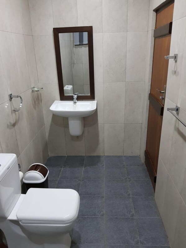 Un baño pequeño con inodoro blanco, lavabo con espejo y puerta de madera.