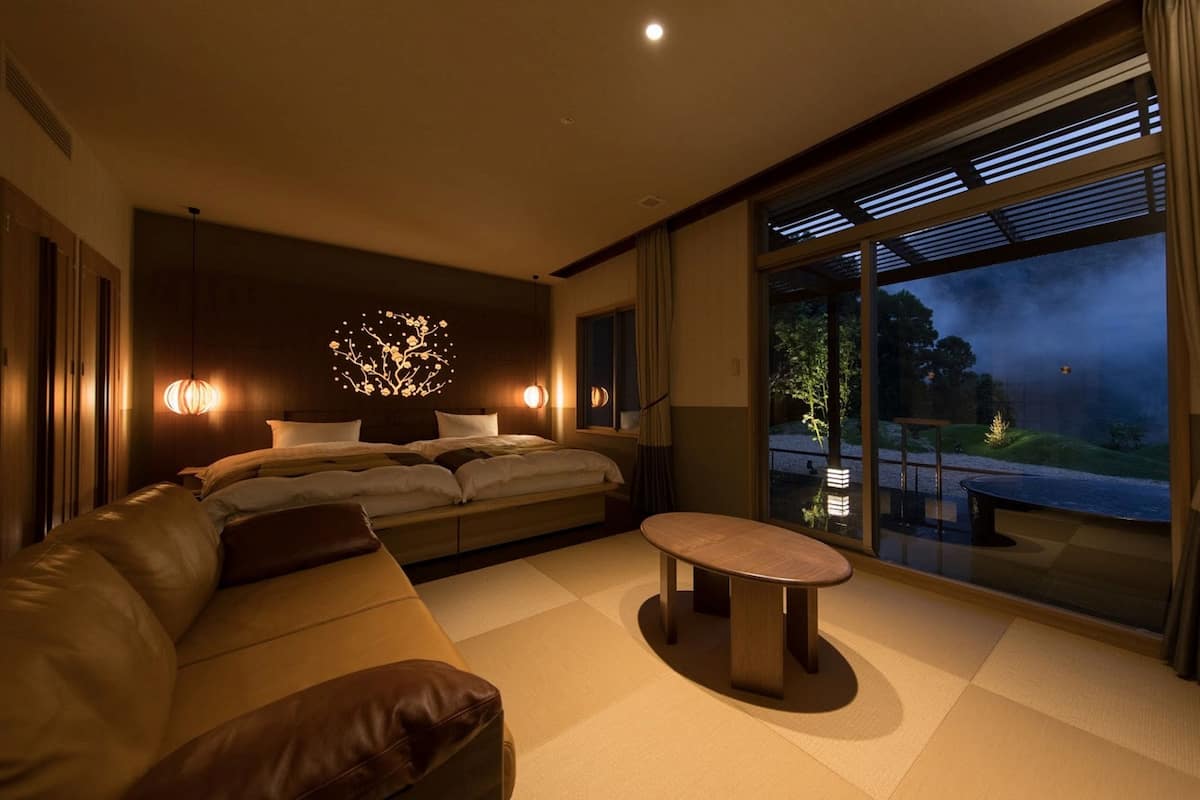 Une chambre d’hôtel moderne dotée d’un grand lit, d’un canapé, d’une petite table et d’une grande fenêtre donnant sur l’extérieur.