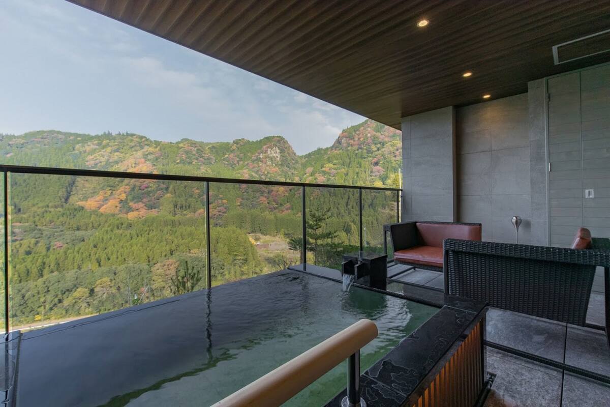Un balcon doté d’une barrière en verre donnant sur un paysage montagneux.