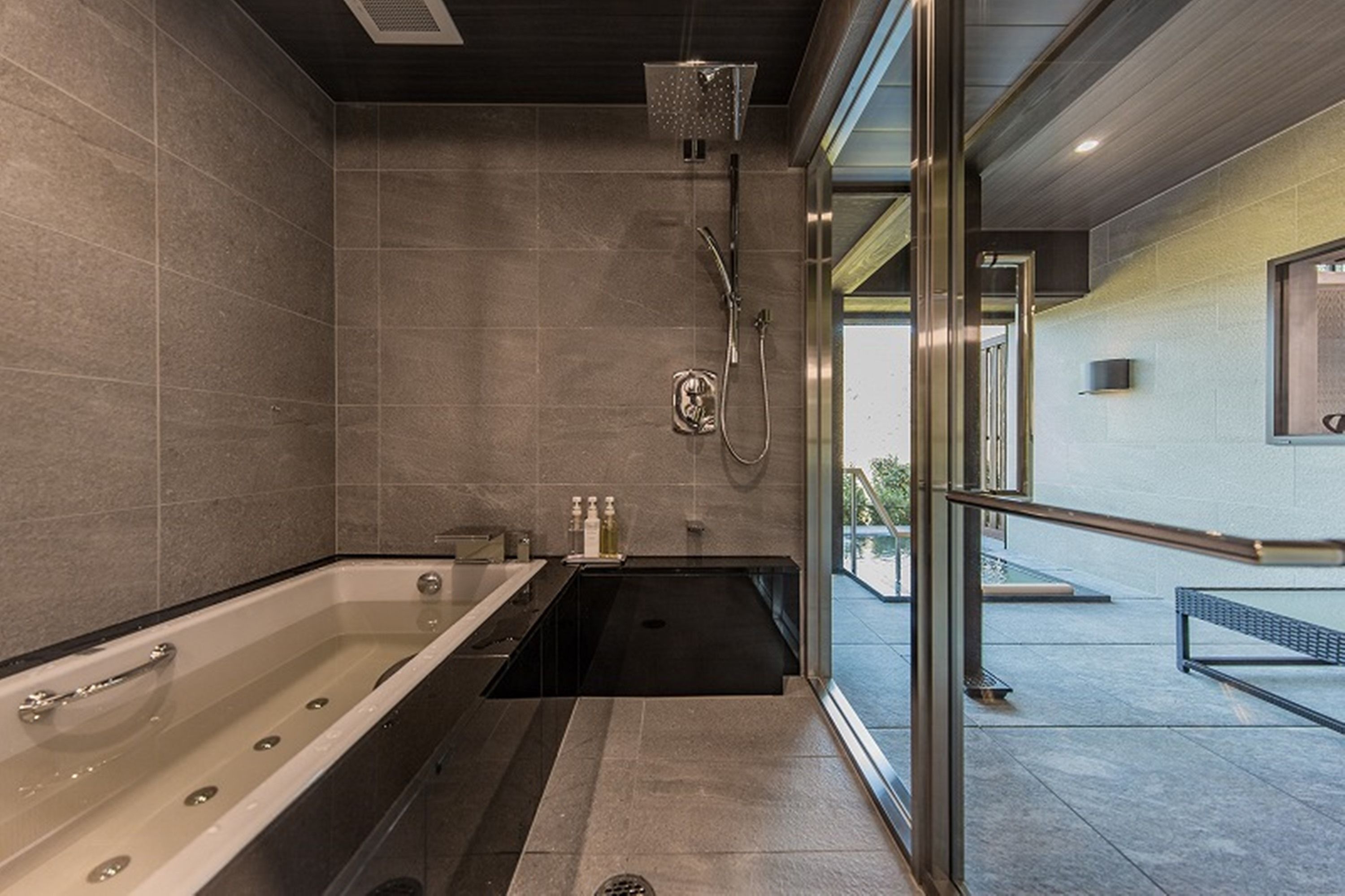 A modern bathroom with a large bathtub, a shower area, and a glass-enclosed window.