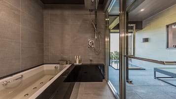 A modern bathroom with a large bathtub, a shower area, and a glass-enclosed window.