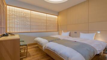 A modern hotel room with two beds, a desk, and a traditional Japanese-style partition.