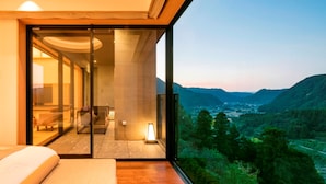 A modern bedroom with a large window overlooking a mountainous landscape.